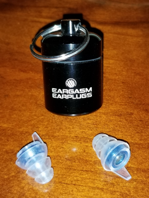 The black metal Eargasm carrying case behind the blue-colored Eargasm silicon earplugs 
