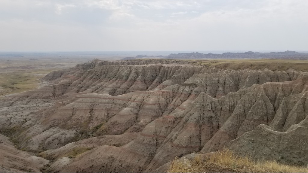 Weather carved hillsides stand in the foreground of Castle Butte as seen from a vista point in Badlands National Park