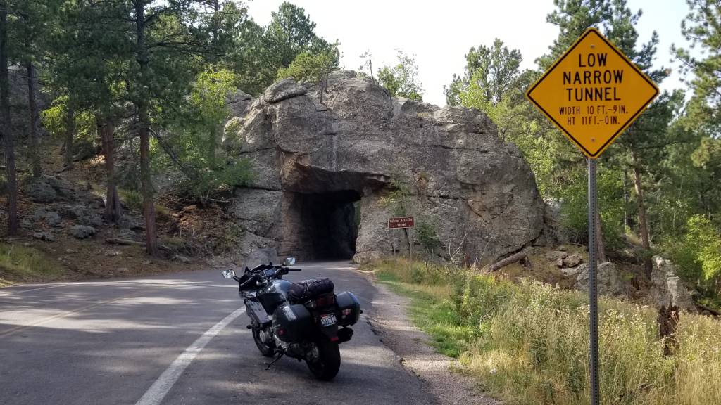 A sign warns of the low clearance and narrow one-lane tunnel ahead on Iron Mountain Road 