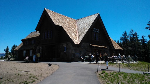 The sharply sloped roof lines of the Crater Lake lodge and visitor center standing against a blue sky 