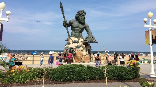 King Neptune statue overlooking a crowded beach on a sunny day at Neptune Park 