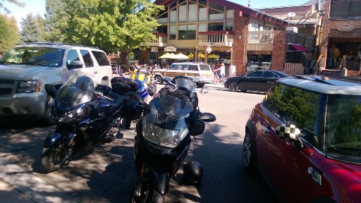 Motorcycles parked in front of a cluster of coffee shops and small businesses in Aspen