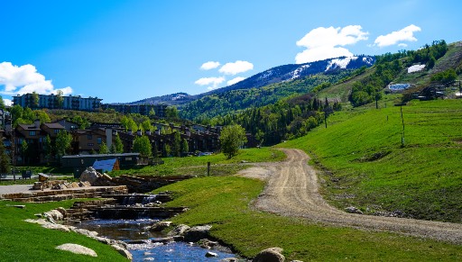 A green field and clear stream against blue skies lead into Steamboat Springs