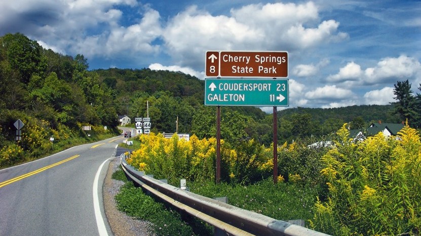 Highway and road sign leading into hills.