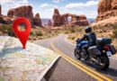 A sport-touring rider travels a winding road through Arches National Park, with a map and location pin highlighting the route.