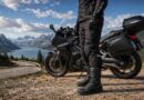 Sport touring boots near a curving mountain road above a lake
