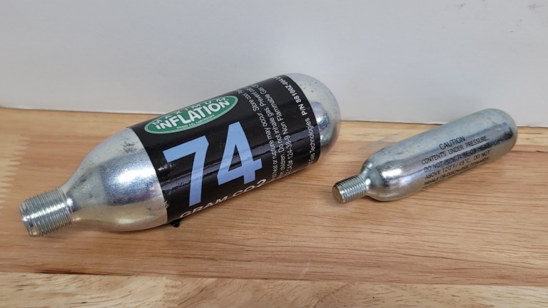 Maximus 74-gram CO2 cartridge beside a 16-gram cartridge